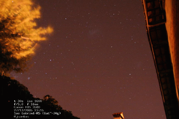 imagem das nuvens como um borrao no ceu noturno com um arbustro no canto superior esquerdo da tela