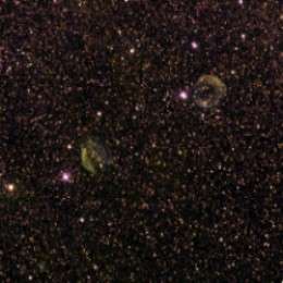 imagem com varias estrelas e duas nuvens de poeira esverdeadas