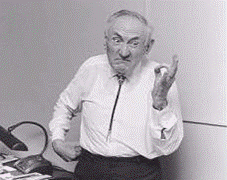 fotos do fisico Fritz Zwich vestindo uma roupa social fazendo uma expressão brava com a mão na cintura e a outra fazendo um ok com os dedos